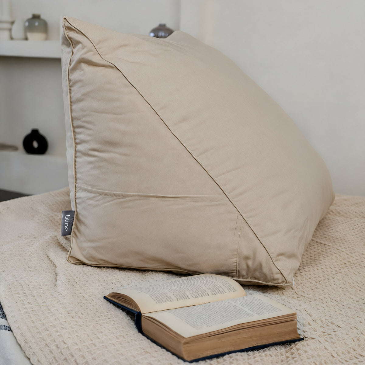 Leeskussen Bline, kleur Beige, op een bed met een opengeslagen boek