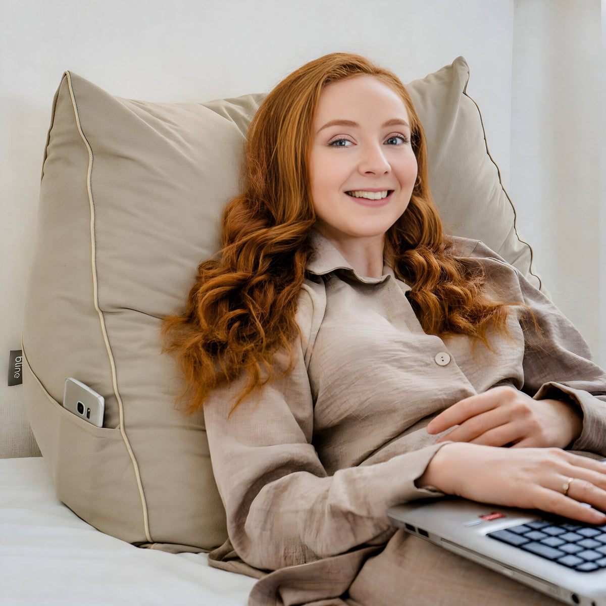Vrouw met laptop tegen het leeskussen Bline, kleur Beige