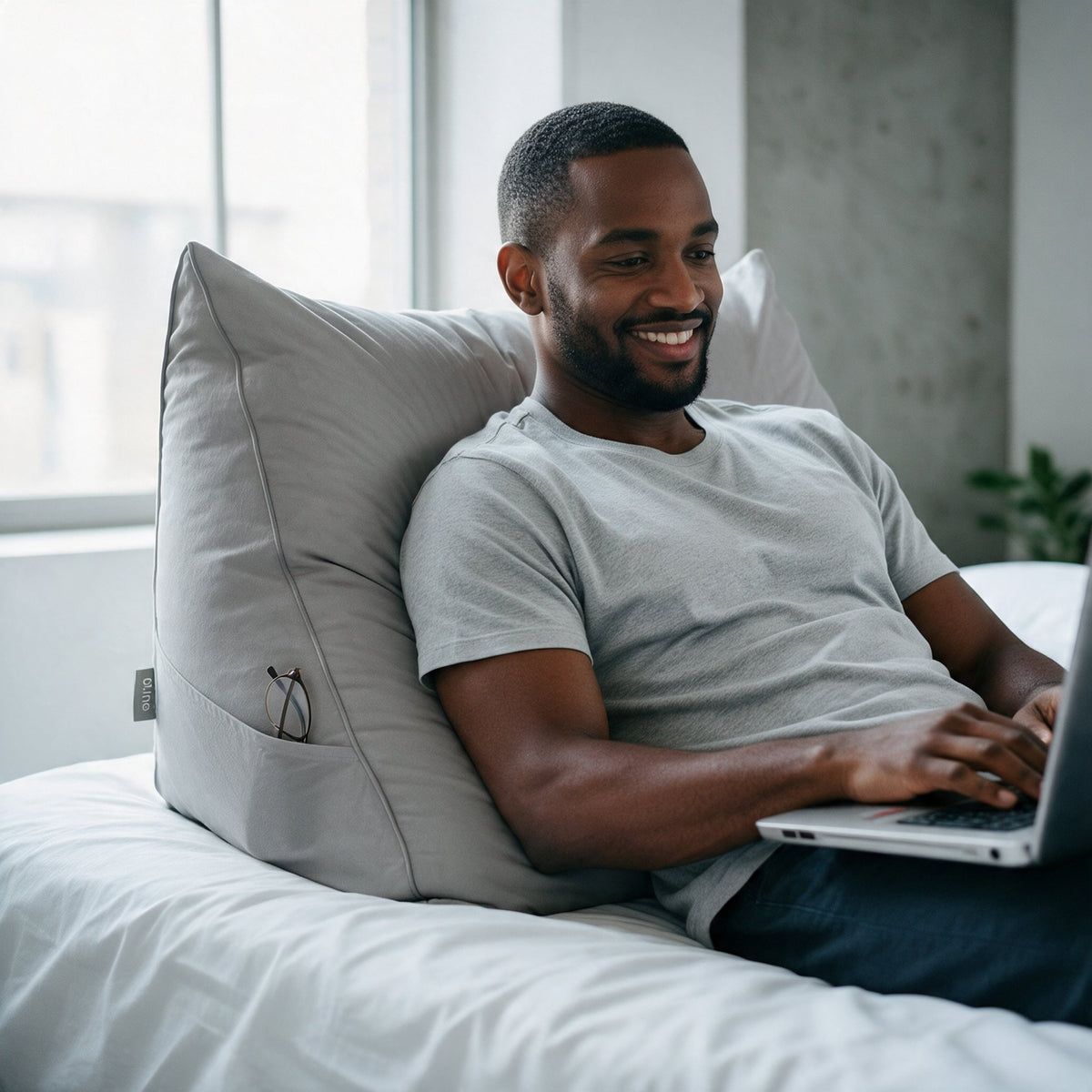 Man met laptop tegen het leeskussen Bline, kleur Grijs