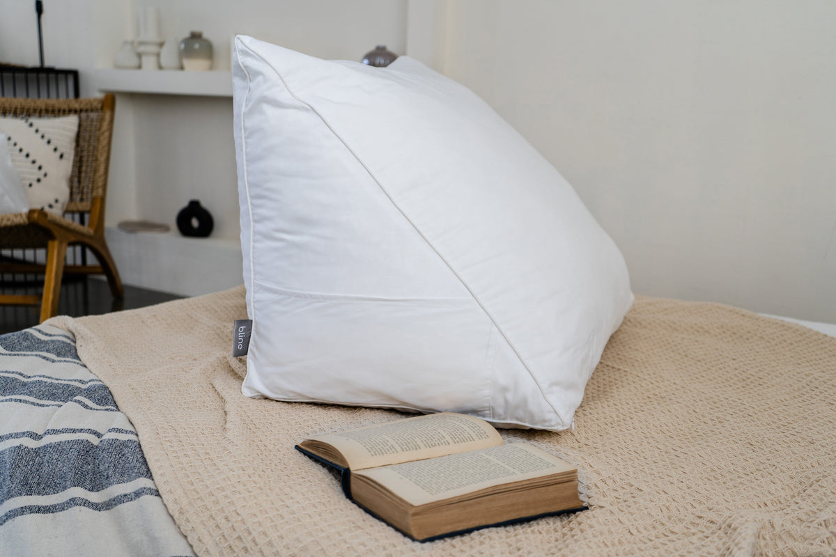 Leeskussen Bline, kleur Wit, op een bed met een open boek ervoor